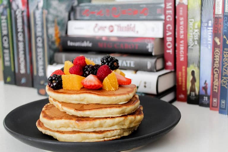 Blueberry Pancakes on Black Plate Near Books